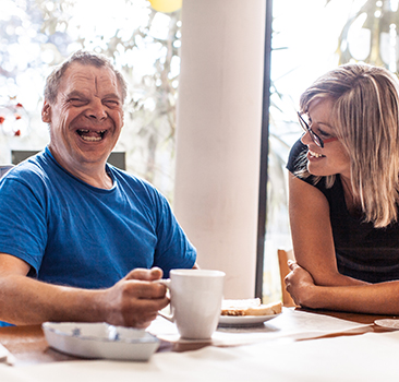 man laughing whilst drinking coffee